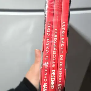 Lombadas vermelhas dos três livros do Curso Básico de Desenho